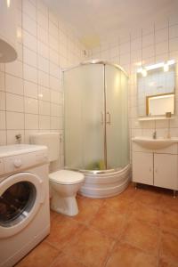 a bathroom with a shower toilet and a washing machine at Apartments by the sea Zavala, Hvar - 8637 in Jelsa