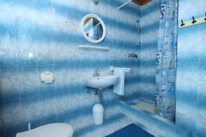 a blue tiled bathroom with a toilet and a sink at Apartment Kraj 8372b in Tkon