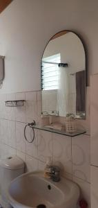 a bathroom with a sink and a mirror and a toilet at Lola's Guest House in Mactan