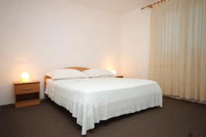 - une chambre avec un lit blanc, une table de chevet et une fenêtre dans l'établissement Family friendly seaside apartments Nevidjane, Pasman - 8394, à Neviđane