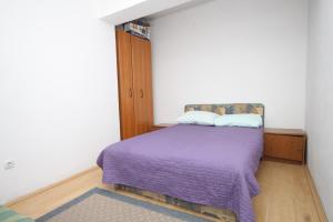 1 dormitorio con 1 cama con manta morada en Apartments by the sea Kukljica, Ugljan - 8402, en Kukljica