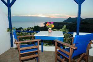a table and chairs on a balcony with a vase of flowers at Sunset Hotel in Agios Ioannis Kaspaka