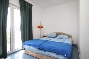 um quarto com uma cama com lençóis azuis e uma janela em Apartments by the sea Tkon, Pasman - 8458 em Tkon
