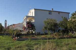 a white building with a garden in front of it at Apartments by the sea Mrljane, Pasman - 8463 in Neviđane
