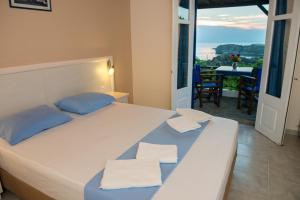 a bedroom with a bed with blue pillows and a balcony at Sunset Hotel in Agios Ioannis Kaspaka