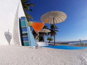 a martini glass sitting on the beach with an umbrella at T-Land Resort in Nembrala