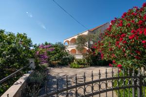 a fence in front of a house with flowers at Apartments with parking space Pasman - 8214 in Pašman