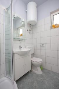 a white bathroom with a toilet and a sink at Apartments by the sea Kali, Ugljan - 8235 in Kali