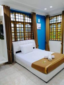 Un dormitorio con una cama blanca y paredes y ventanas azules. en Irama Banglo with Private Pool, en Bachok