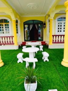 Habitación con mesas blancas y sillas sobre hierba verde en Irama Banglo with Private Pool, en Bachok