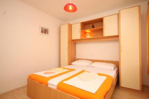 a bedroom with a bed with an orange and white blanket at Apartments by the sea Cavtat, Dubrovnik - 8610 in Cavtat