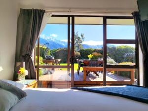 Te Mahuru Retreat في كايكورا: غرفة نوم بسرير وشرفة مطلة