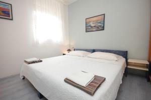 a bedroom with a large white bed with towels on it at Apartments by the sea Ugljan - 8519 in Ugljan