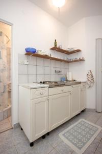 a kitchen with white cabinets and a sink at Apartments by the sea Ugljan - 8519 in Ugljan