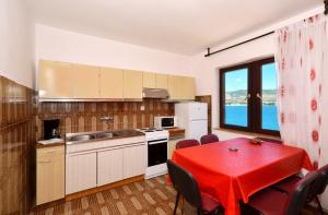 a kitchen with a table with a red table cloth on it at Apartments by the sea Arbanija, Ciovo - 8651 in Trogir