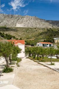 a house on a gravel road with a mountain in the background at Family friendly seaside apartments Duce, Omis - 8668 in Duće