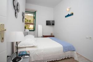 a white bedroom with a bed and a window at Family friendly seaside apartments Duce, Omis - 8668 in Duće