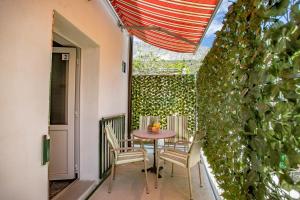 a table and chairs on a patio with a green wall at Family friendly seaside apartments Duce, Omis - 8668 in Duće