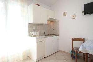 uma pequena cozinha com armários brancos e uma mesa em Apartments and rooms by the sea Kukljica, Ugljan - 8408 em Kukljica
