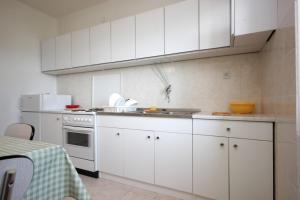 una cucina con armadi bianchi e un piano cottura bianco con forno di Apartments by the sea Suhi Potok, Omis - 8676 a Dugi Rat (Punta Lunga)