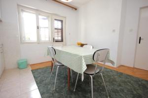 - une table et des chaises dans une chambre blanche dotée d'une fenêtre dans l'établissement Apartments by the sea Suhi Potok, Omis - 8676, à Dugi Rat