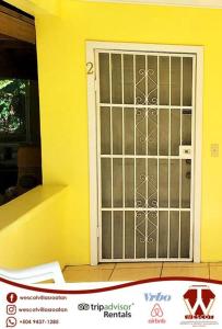 a door to a yellow house with a window at 2 bedroom apartmen in the heart of west end! in Roatan