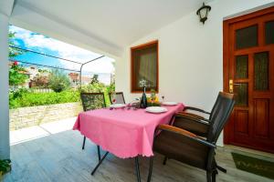 einen Tisch mit einem rosa Tischtuch auf einer Terrasse in der Unterkunft Family friendly apartments with a swimming pool Biograd na Moru, Biograd - 8370 in Biograd na Moru