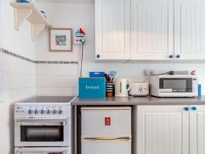 a kitchen with white cabinets and a white stove top oven at Sea View in Penzance