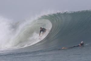 Sirena Surf Lodge Miramar Nicaragua في Miramar: رجل يركب الأمواج على لوح التزلج في المحيط