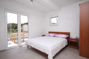a white bedroom with a bed and a balcony at Apartments by the sea Basina, Hvar - 8754 in Vrbanj