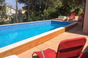a swimming pool with two red chairs and a red at Holiday house with a swimming pool Basina, Hvar - 8731 in Vrbanj