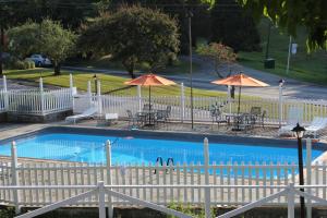 Brewster的住宿－海蒂旅館，一个带桌椅和遮阳伞的游泳池