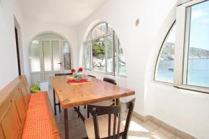 uma sala de jantar com uma mesa de madeira e janelas em Apartments and rooms by the sea Cove Zarace - Dubovica, Hvar - 8781 em Zarače