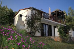 a white house with a balcony and purple flowers at Apartments with a parking space Zavala, Hvar - 8706 in Jelsa +13 photos