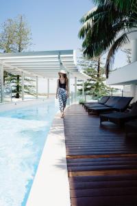 a woman walking down a walkway next to a pool at Rumba Beach Resort in Caloundra