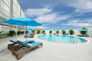 una piscina con sombrillas y sillas azules junto a un edificio en Eastin Grand Hotel Saigon en Ho Chi Minh