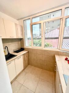a small kitchen with white cabinets and windows at Apartment modern in Sulina in Sulina