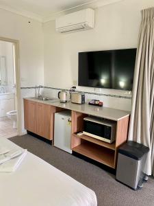 a hotel room with a kitchen with a microwave and a tv at Beautiful Villa in the heart of the Hunter Valley in Pokolbin