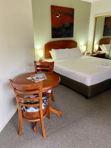 ポーコルビンにあるBeautiful Villa in the heart of the Hunter Valleyのベッド、テーブル、ベッドが備わるホテルルームです。