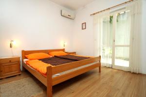 - une chambre avec un lit doté d'oreillers orange et une fenêtre dans l'établissement Apartments with a parking space Mlini, Dubrovnik - 8834, à Mlini