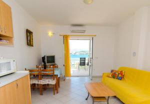 ein Wohnzimmer mit einem gelben Sofa und einem Tisch in der Unterkunft Apartment Okrug Gornji 8440c in Trogir