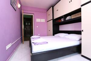 sypialnia z fioletowymi ścianami i dużym łóżkiem w obiekcie Apartment Zecevo Rtic 10334a w Rogoznicy
