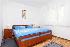 a bedroom with a bed with blue sheets and a window at Apartments with a parking space Omis - 10349 in Omiš