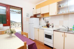 eine Küche mit weißen Geräten und einem Tisch mit einem lila Tischtuch in der Unterkunft Apartments by the sea Drvenik Veliki, Drvenik - 10346 in Drvenik Veli