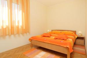 ein Schlafzimmer mit einem Bett mit orangefarbener Bettwäsche und einem Fenster in der Unterkunft Apartments by the sea Drvenik Veliki, Drvenik - 10346 in Drvenik Veli