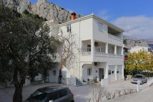 a white building with a mountain in the background at Apartments with a parking space Omis - 10351 in Omiš