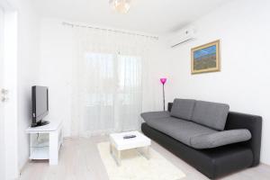 sala de estar con sofá negro y TV en Apartments with a parking space Omis - 10362, en Omiš