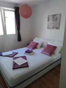 a bed with purple and white pillows and a window at Apartments with parking space Stanici, Omis - 10360 in Celina