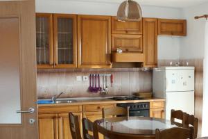 a kitchen with wooden cabinets and a table and a refrigerator at Apartments with parking space Stanici, Omis - 10360 in Čelina