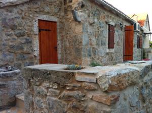 een oud stenen gebouw met een houten deur bij Holiday house with a swimming pool Vrbanj, Hvar - 11040 in Vrbanj